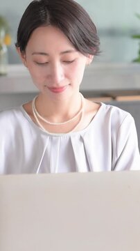 オシャレな明るいオフィスでノートパソコンで仕事をする日本人女性 オフィスワーク・ビジネスシーン縦動画