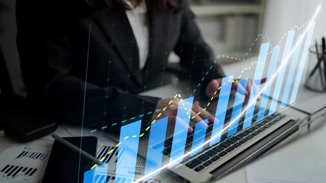 A business professional engages with financial charts and graphs on a laptop in a modern office setting, showcasing analysis and growth opportunities. Copula