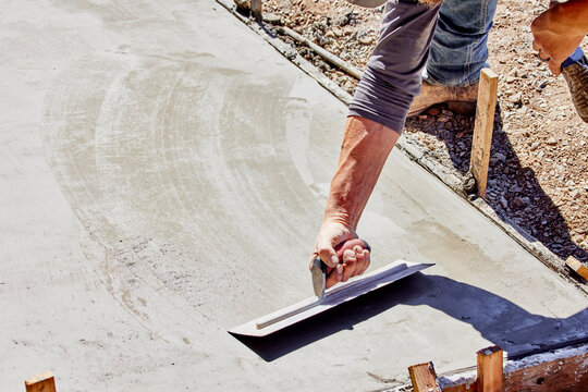 Cement Worker using a Hand Trowel to Smooth Wet Cement