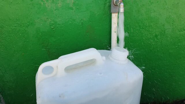 Plastic jerry can container being filled with fresh water for storage or emergency supply.