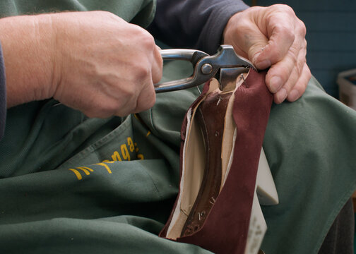 Fixing footwear. Professional shoemaker. Unrecognizable craftsman hands working with metal pliers at factory for handmade occupation.
