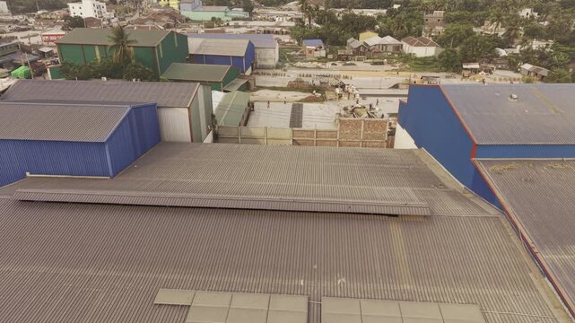 Drone footage flying over a large rice processing factory in the Khajanagar industrial area of Kushtia, Bangladesh, showing factory buildings, warehouses, and production facilities.