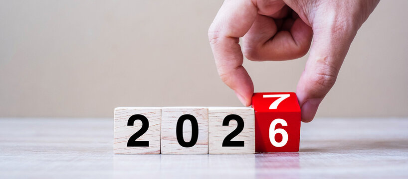 hand flipping block 2026 to 2027 text on table. Resolution, strategy, plan, goal, motivation, reboot, business and New Year holiday concepts