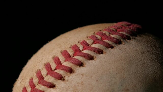 A closeup of a well worn baseball rotating isolated against a black background. Sports or game ball concept with copy space.