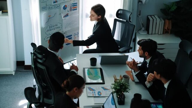 Top view of smart manager project pointing at whiteboard with mind map and financial graph and explain marketing idea while diverse investors listening and analyze stock investment chart. Directorate.