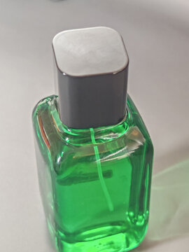 Transparent green glass cosmetic bottle with white cap on a clean minimal background, representing skincare packaging, beauty product design, freshness, purity, and modern personal care concept.