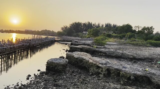 Scenic golden sunset over calm river with wooden footbridge and natural shoreline