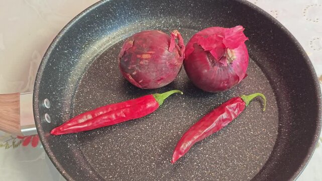 Arranging Red Chili Peppers and Red Onions Inside a Frying Pan