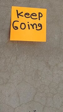Sticky Note with Encouraging Phrase Keep Going on Wall
