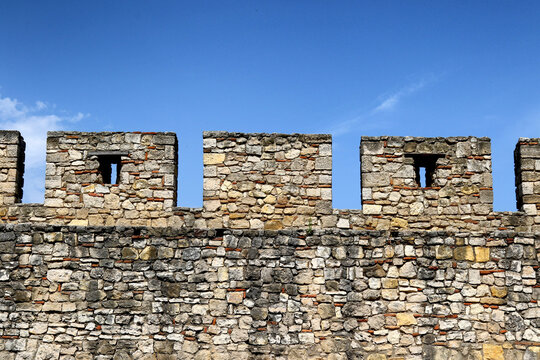 Stone battlement wall with embrasures at Kalemegdan Fortress under a clear blue sky, Belgrade, Serbia