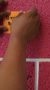 Placing Sticky Note with Phrase Dream Big on Pink Wall
