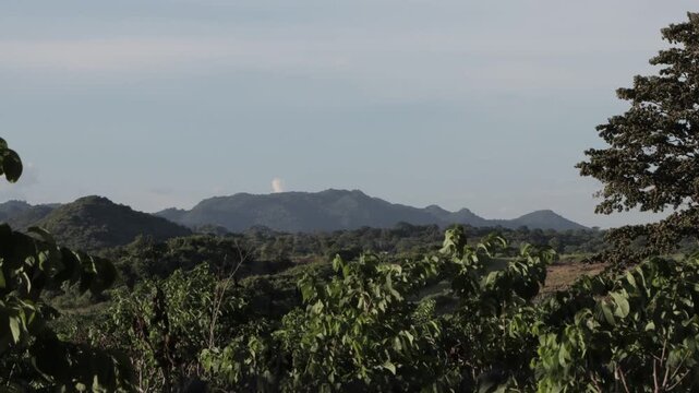 Timelapse of scenic green mountain range and tropical forest under clear blue sky. Bright daytime nature landscape.