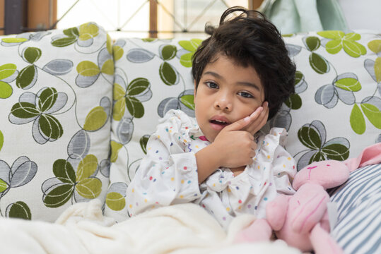 Sad preschooler girl suffering from toothache touching her swollen cheek while staring directly at camera. Showcasing pediatric dental problems, childhood illness, and oral healthcare