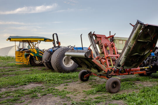 Row of specialized farm machinery including mower and tractor used for cutting sod turf