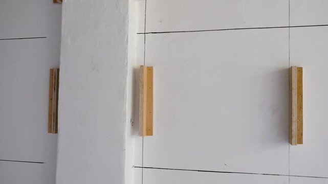 White wall marked with grid lines and wooden cleats for paneling
