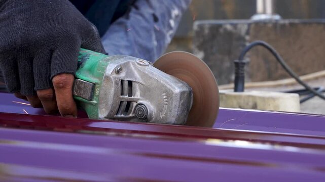 Close up of angle grinder cutting metal roof sheet with flying sparks