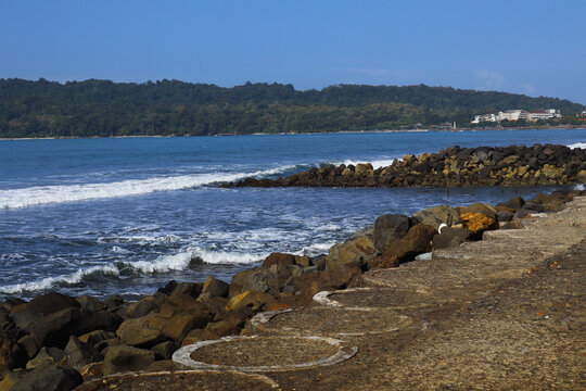 Scenic Tropical Bay with Rocky Breakwater and Concrete Pier - Ocean Waves and Forested Hills