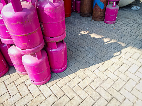 Pink 12 kg LPG cylinders stacked side by side in the area outside the warehouse.