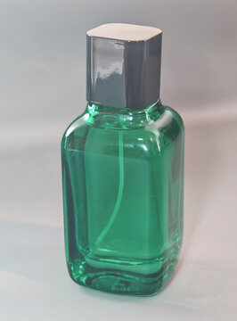 Transparent green glass cosmetic bottle with white cap photographed on a clean minimal background, representing skincare packaging, beauty product design, freshness, purity, and modern personal care