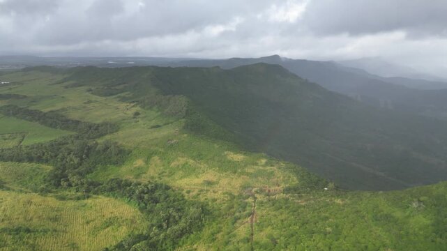 Drone aerial view of Montagne du Rempart near Flic en Flac, Mauritius. Lush green mountain landscape and rugged topography under an overcast cloudy sky. Tropical island nature panorama.