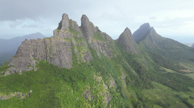 Aerial drone view of the rugged Montagne du Rempart peaks near Flic en Flac, Mauritius. Lush green vegetation clinging to the steep volcanic rock faces of this iconic island mountain.