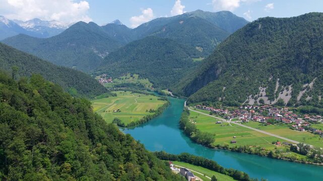 Aerial view of Most na Soci town in Soca Valley, Slovenia, showing the settlement, turquoise lake, surrounding hills, and natural landscape - drone shot