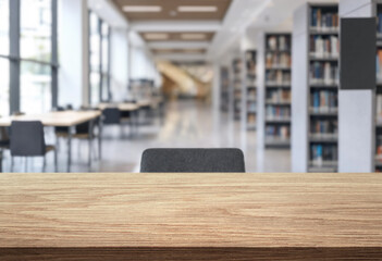 empty desk against blurred background of public library with bookshelves © Agil