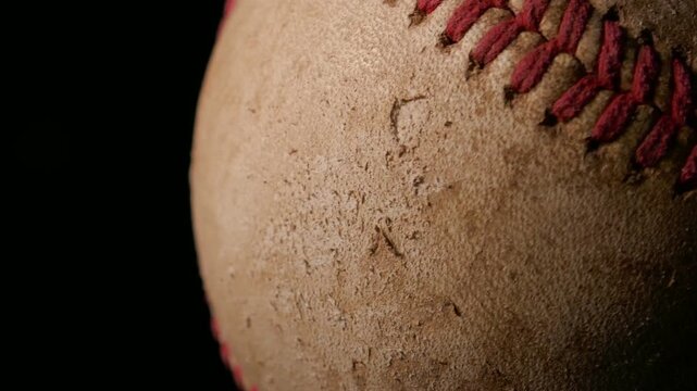 A closeup of a well worn baseball rotating isolated against a black background. Sports or game ball concept with copy space.