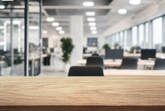 wooden desk on foreground and blurred background of an office interior