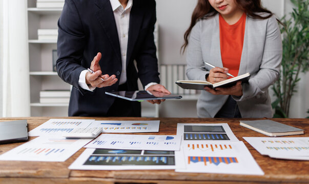 Business professionals collaborating in an office. Reviewing financial documents and digital data on a tablet