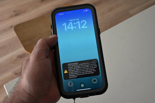 AUS Alert Signal on Smartphone in Man's Hand &ndash; Australian Emergency Alert Concept