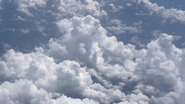 Airplane window view of puffy white clouds from above