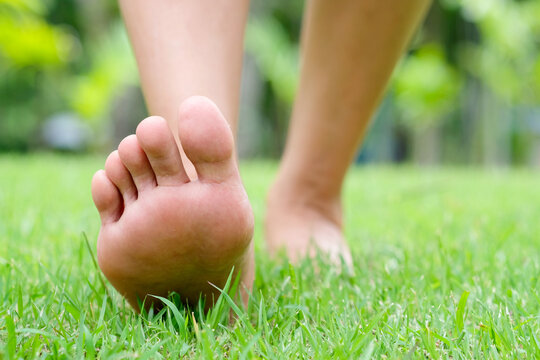Woman walking barefoot on green grass, capturing a natural moment of grounding, relaxation, and connection with nature and wellness concept 