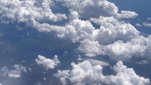 Airplane window view of puffy white clouds from above