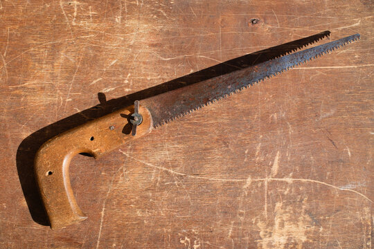 Vintage hand saw with wooden handle on rustic background