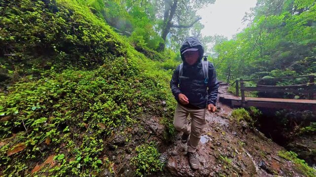 Adventurous man hiking on a wet rocky trail