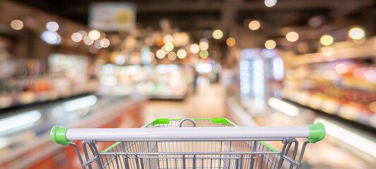 empty shopping cart in supermarket aisle blurred background © Kwangmoozaa