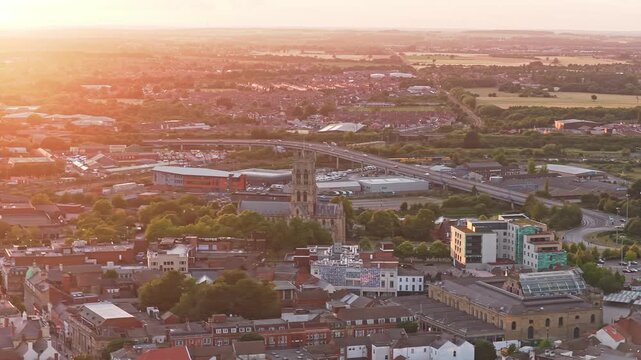 Doncaster Minster rises beside St George's Bridge and A19 St George's Way in Doncaster, South Yorkshire, England, United Kingdom, surrounded by the historic urban core, drone lateral slide.