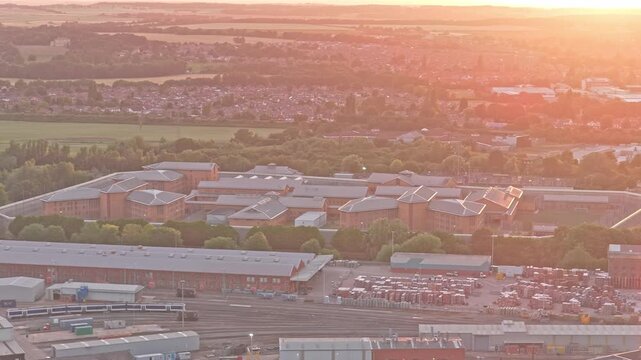 HMP Doncaster prison at Marshgate, Doncaster South Yorkshire, England, United Kingdom, stands beyond extensive railway infrastructure and depot facilities, drone pullback.