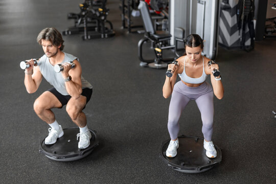 Athletic couple doing exercise on BOSU ball at gym