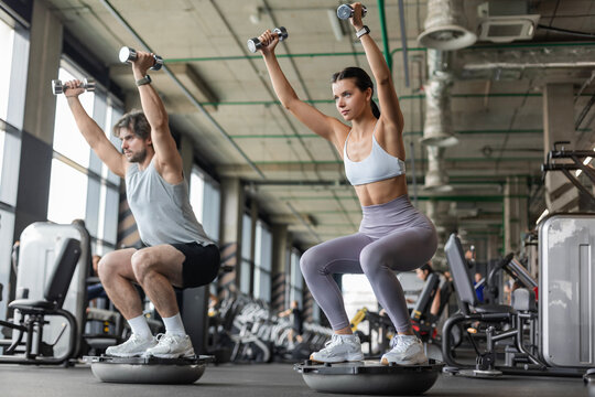Athletic couple doing exercise on BOSU ball at gym