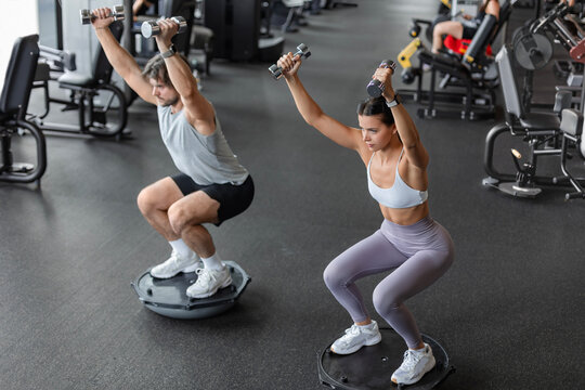 Athletic couple doing exercise on BOSU ball at gym