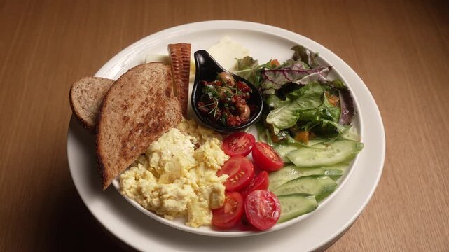 Delicious and healthy Turkish breakfast plate with assorted cheeses, scrambled eggs, and fresh vegetables