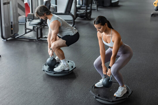 Athletic couple doing exercise on BOSU ball at gym