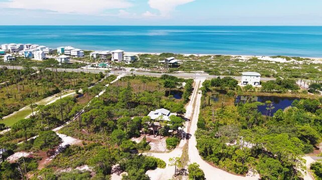 Drone orbit of 30E roadside area with empty vacant lots beside inner wetlands on beautiful tropical environment, Cape San Blas, Florida, US