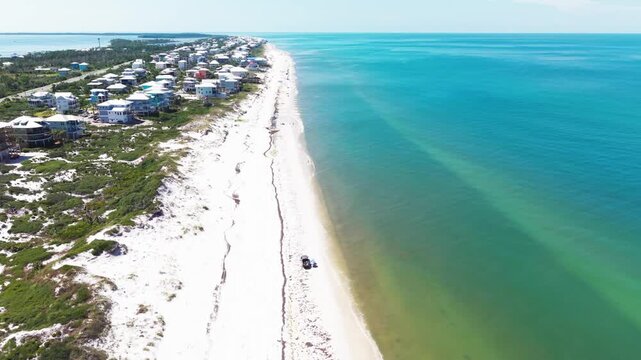 Aerial orbit fly over pristine white sandy Cape San Blas beach coastline on barrier island stretching beside turquoise Gulf of Mexico waters, Florida, US