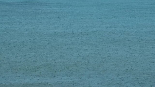 Heavy raindrops falling on turquoise sea surface, tropical monsoon rainy season background, oceanic weather patterns, nature documentary, slow motion