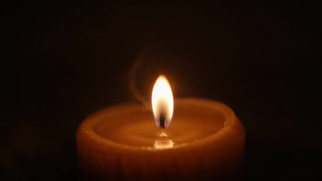 Cinematic candle flame fire light in darkness with warm glow bokeh background closeup tranquil night atmosphere for meditation calm spiritual reflection and peaceful mood