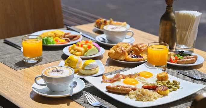 Gourmet breakfast spread sitting on wooden table in sunny outdoor cafe, bright natural light, luxury hotel brunch, hospitality travel lifestyle.