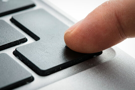 Finger pressing the enter key on a laptop keyboard